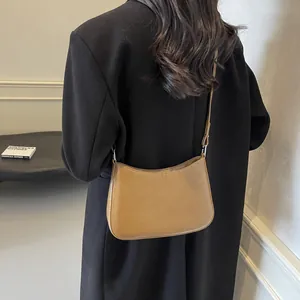 Detail of tan leather baguette bag showing adjustable strap and NO FILTER print