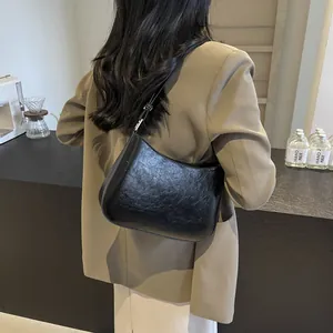 Detail of black glossy crescent bag with crinkled leather texture on model in a cafe