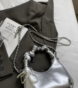 Detail of silver pleated handbag featuring an adjustable metal chain with a ball slide buckle
