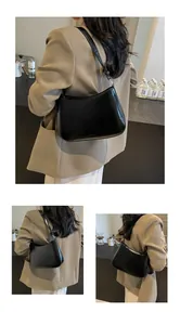 Detail view of a black minimalist leather underarm bag with an adjustable shoulder strap