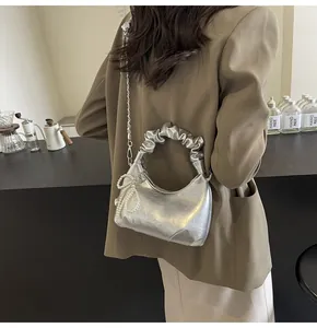 Détail du sac à main plissé argenté avec breloque perle et bandoulière chaîne