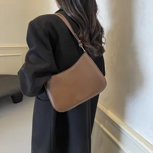 Close-up of brown leather shoulder bag featuring fine texture and adjustable strap