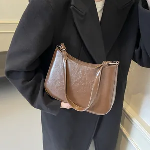 Brown leather crescent shoulder bag with vintage texture and silver hardware details