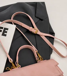 Detail of adjustable shoulder strap and gold hardware on light pink crossbody bag