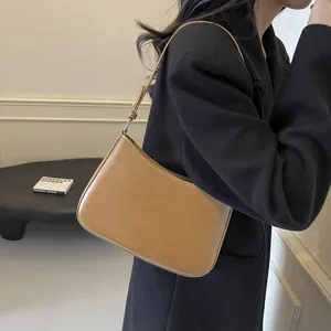 Detail of light brown leather underarm bag featuring the NO FILTER logo on the base