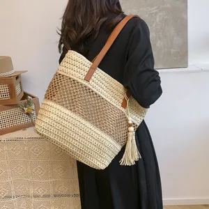 Summer woven tote bag with brown leather straps and tassels in a boho vacation style