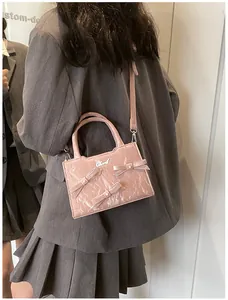 Détail du sac à main rose à nœuds en texture plissée brillante avec logo en métal