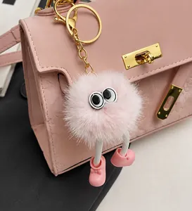 Detail of pink furry monster keychain charm on pink litchi pattern handbag side