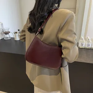 Macro detail of wine red crescent shoulder bag featuring refined NO FILTER embossed logo