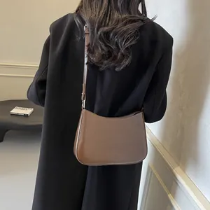 Minimalist brown leather half-moon shoulder bag with NO FILTER embossing on a model
