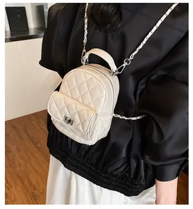 Detail van gebroken witte mini-rugzak met ruitpatroon, zilveren ketting en draaisluiting