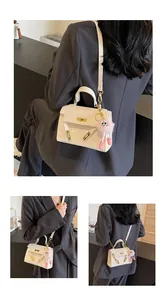 White embossed texture top-handle bag with a cute pink plush charm and gold turn-lock detail