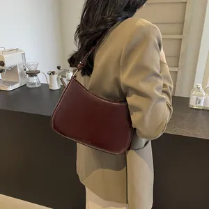Detail of a dark red glossy leather hobo bag worn with a khaki professional suit