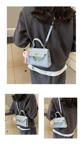 Detail of light blue crossbody bag with gold-tone hardware and plush pink charm accessory