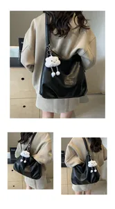 Macro view of black leather tote bag featuring a cute white cloud plush pendant accessory
