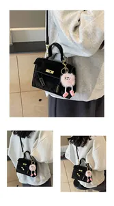 Close-up of black velvet crossbody bag with golden hardware and pink plush charm