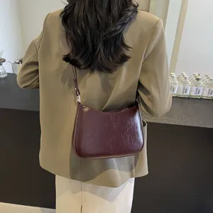 Burgundy faux leather shoulder bag with NO FILTER print worn by model in green suit