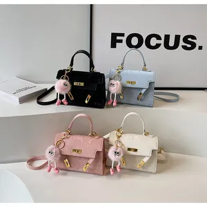 Detail shot of four small satchel bags in black, blue, pink, and white with cute pom charms