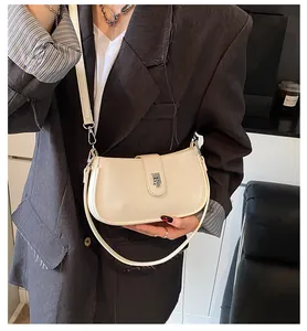 Detail of cream white faux leather saddle bag with silver buckle and dual straps