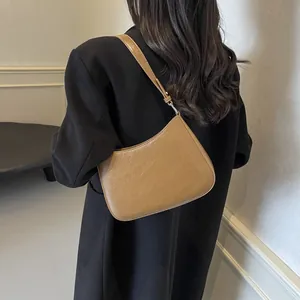 Detail of light brown PU leather hobo bag with embossed lettering on black blazer