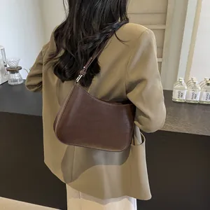 Minimalist dark brown leather underarm bag with smooth texture worn on the shoulder