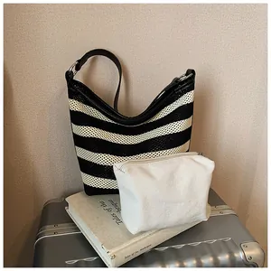 Detail of striped knit tote bag with white canvas pouch on a travel suitcase