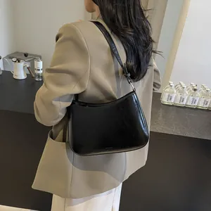 Minimalist black shiny leather hobo bag for women worn with khaki blazer for commute