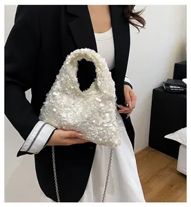 Close-up of white sequined handbag with metal chain strap and shimmering texture