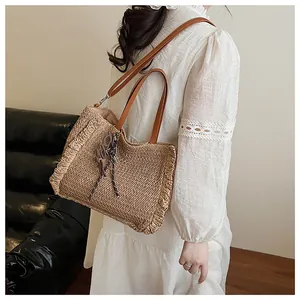 Detail van strooien tas met franjes, leren handvatten en geometrische hanger