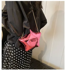 Macro shot of metallic pink star bag with golden chain strap on model's shoulder
