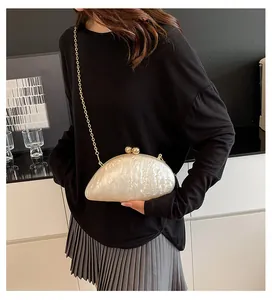 Detail of shell-shaped acrylic evening bag with pearlescent finish and gold chain strap
