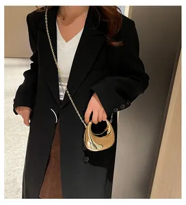 Detailed view of the mini golden crescent handbag with chain strap shown on a model