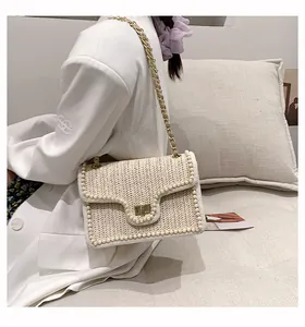 Dettaglio borsa di paglia beige con perle, chiusura dorata e tracolla a catena