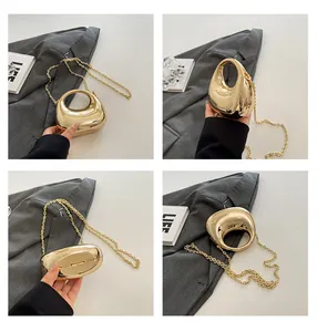 Macro view of golden pebble shaped acrylic evening bag with metallic mirror finish