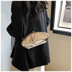 Polished silver bean-shaped acrylic clutch with thin chain strap worn by a model