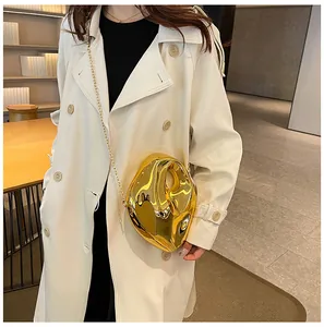 Detail of a liquid-shaped gold acrylic evening bag with a metallic chain strap and mirror finish