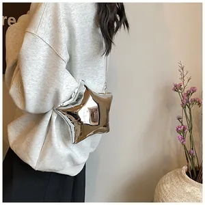 Detalle de bolso bandolera plateado en forma de estrella con acabado metálico fino