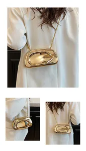 Detail of gold mirror-finish asymmetric sculptural clutch bag with fine chain strap