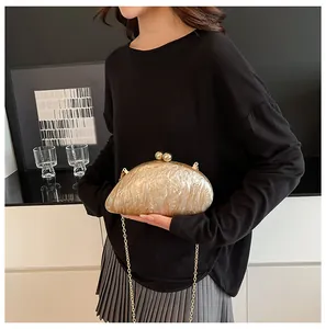 Detailed close-up of golden acrylic evening clutch with marble texture and chain strap