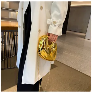 Close-up of golden irregular lava-shaped evening bag with metallic chain on model