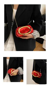 Detail of a luxury red oval clutch bag featuring a prominent gold circular metal handle
