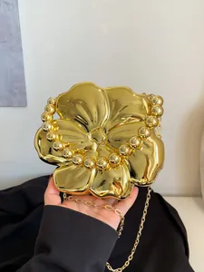 Dettaglio della borsa da sera a fiore dorata con finitura a specchio e manico a perline