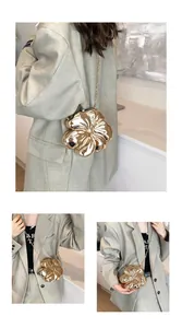 Dettaglio di una pochette a fiori 3D dorata con petali rifiniti e tracolla a catena