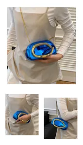 Detail of blue metallic hard-shell clutch with oversized gold ring buckle and chain strap