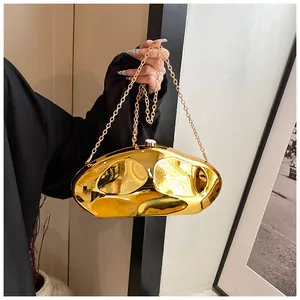 Close-up of golden irregular metallic clutch bag with polished surface and chain strap