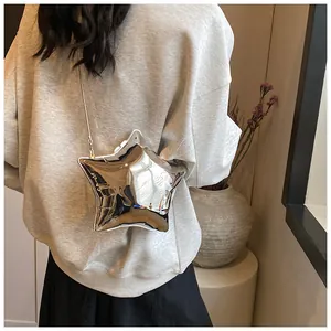 Bolso bandolera plateado con forma de estrella y cadena sobre el hombro del modelo