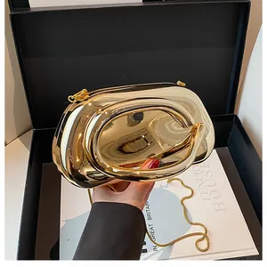Detail of a luxury gold metallic evening clutch with a sleek ring handle and chain strap
