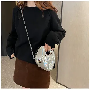 Silver liquid metal crossbody bag with irregular heart design and chain strap on model