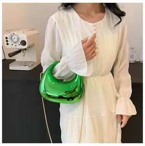 Close-up of bright green metallic crescent bag with gold chain strap on a model