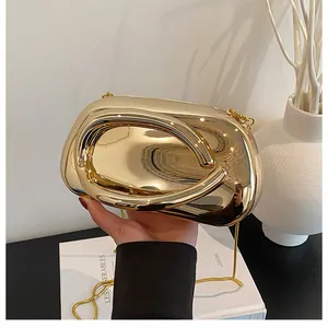 Detail of luxury gold hardshell clutch bag with interlocking metal rings and chain strap
